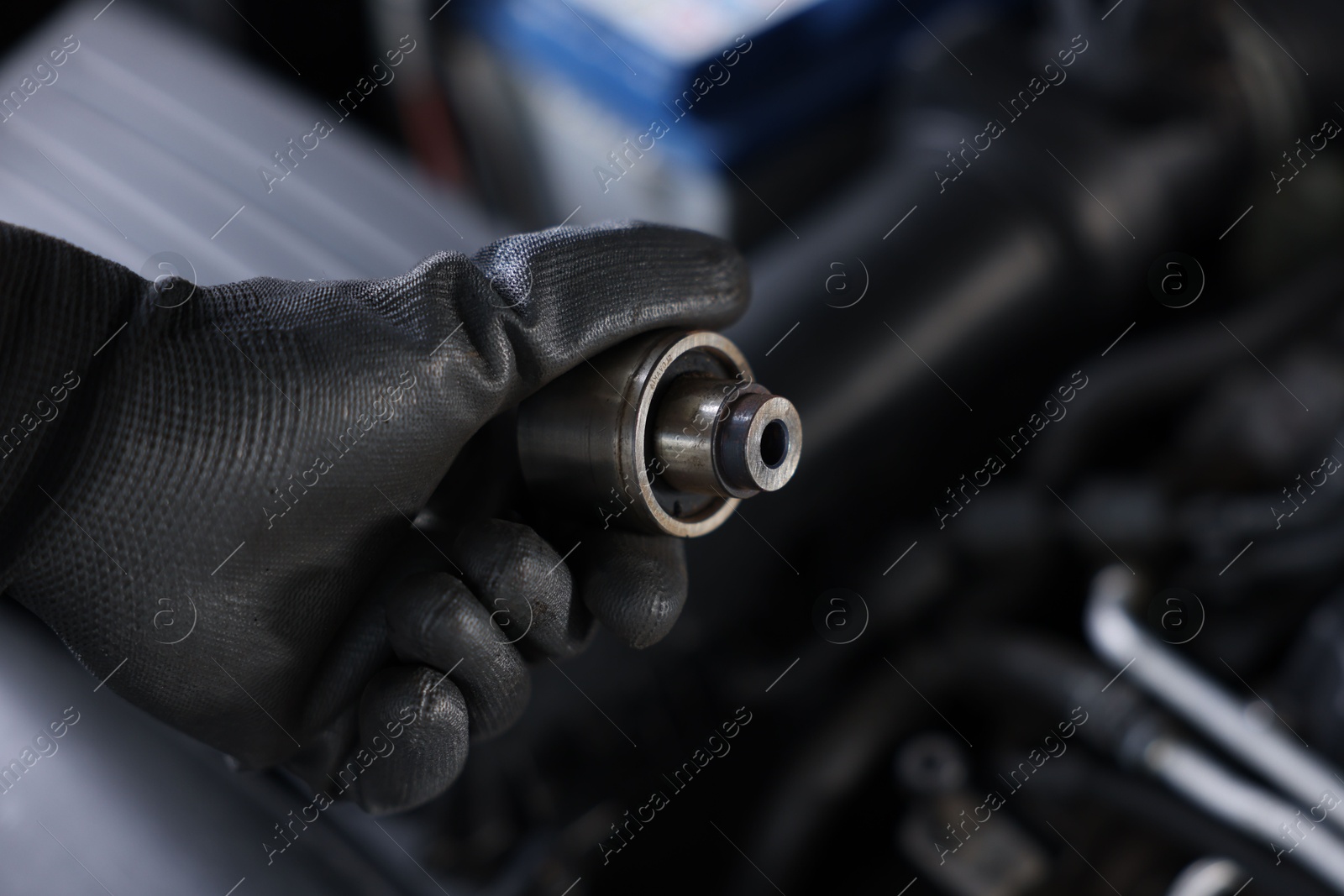 Auto part. Professional mechanic with bearings near open hood of car indoors, closeup. Space for text Photo of Auto part. Professional mechanic with bearings near open hood of car indoors, closeup. Space for text