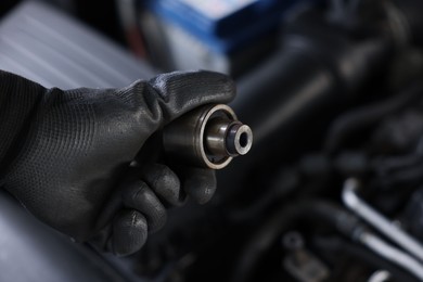 Photo of Auto part. Professional mechanic with bearings near open hood of car indoors, closeup. Space for text