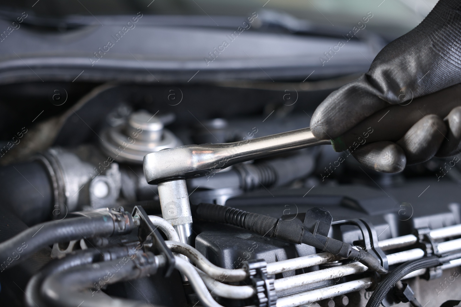 Auto parts. Professional mechanic with torque wrench fixing car indoors, closeup Photo of Auto parts. Professional mechanic with torque wrench fixing car indoors, closeup