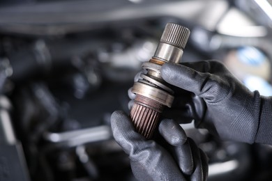 Photo of Auto part. Professional mechanic with drive shaft near open hood of car indoors, closeup. Space for text
