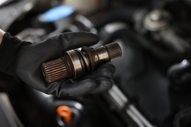 Photo of Auto part. Professional mechanic with drive shaft near open hood of car indoors, closeup. Space for text