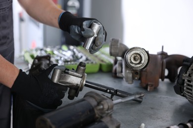 Photo of Auto parts. Professional mechanic fixing manual transmission at grey table indoors, closeup