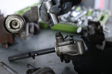 Photo of Auto parts. Professional mechanic fixing manual transmission at grey table indoors, closeup