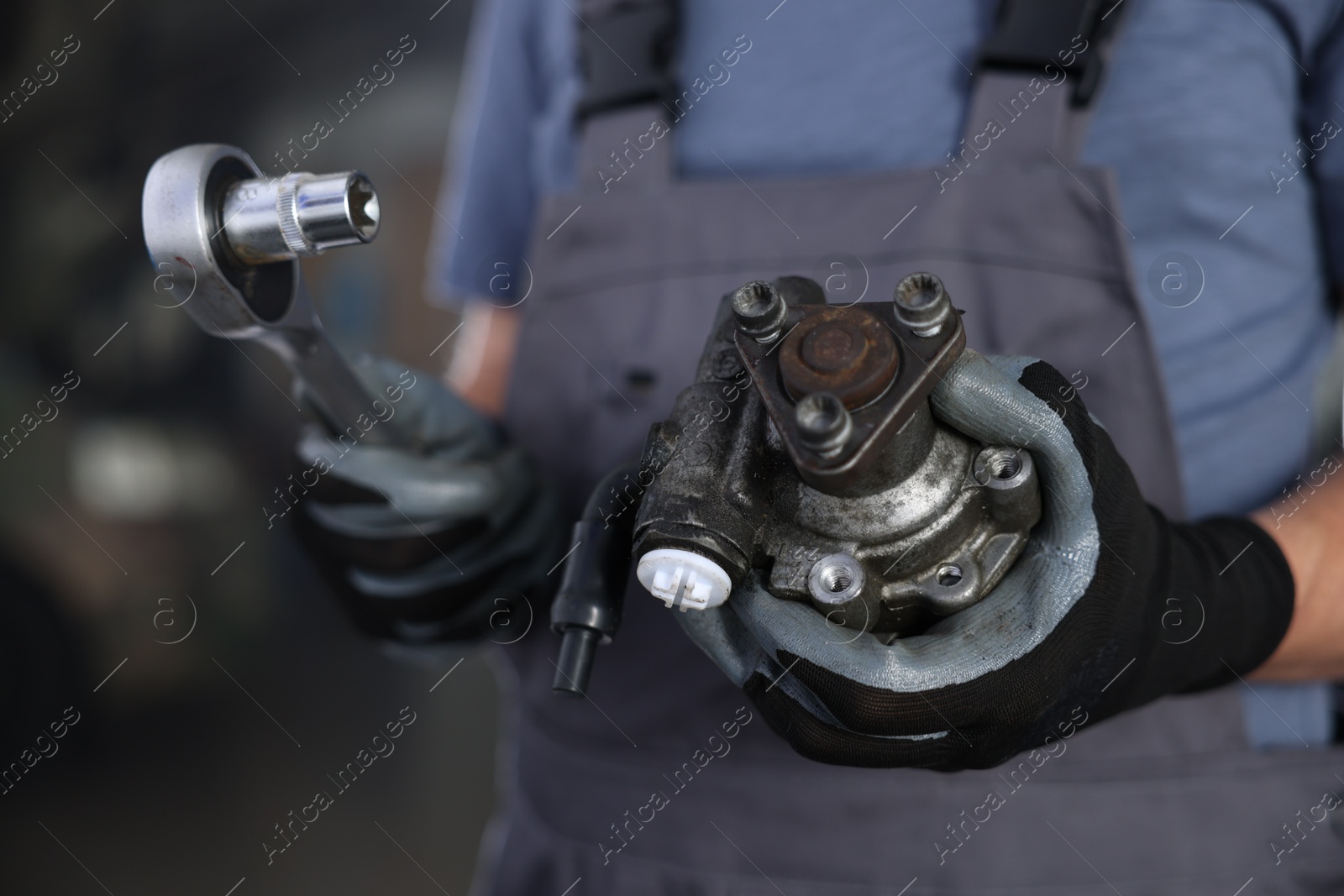 Auto part. Professional mechanic with hydraulic pump and socket wrench indoors, closeup Photo of Auto part. Professional mechanic with hydraulic pump and socket wrench indoors, closeup