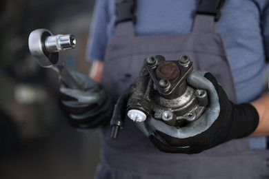 Photo of Auto part. Professional mechanic with hydraulic pump and socket wrench indoors, closeup