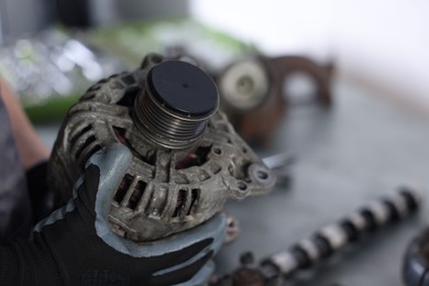 Photo of Auto parts. Professional mechanic with alternator near indoors, closeup. Space for text