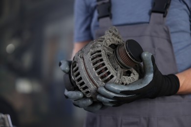 Photo of Auto part. Professional mechanic with alternator near indoors, closeup. Space for text