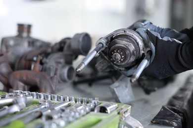 Photo of Auto parts. Professional mechanic with starter motor at table indoors, closeup