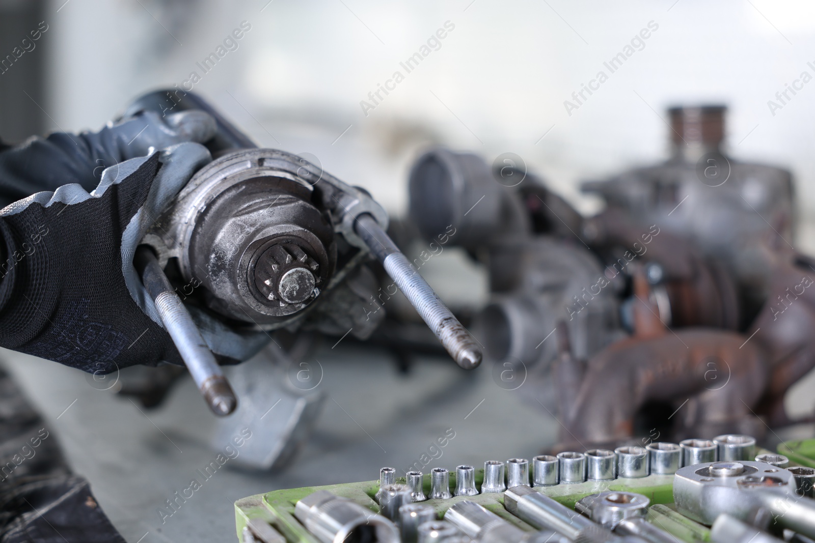 Auto parts. Professional mechanic with starter motor at table indoors, closeup. Space for text Photo of Auto parts. Professional mechanic with starter motor at table indoors, closeup. Space for text