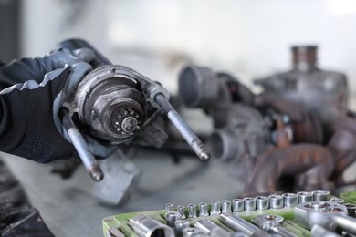 Photo of Auto parts. Professional mechanic with starter motor at table indoors, closeup. Space for text