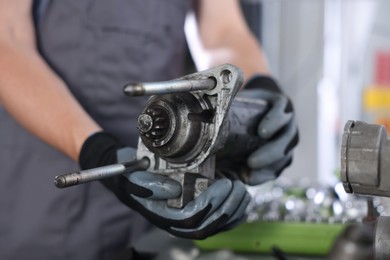 Photo of Auto part. Professional mechanic with starter motor indoors, closeup