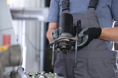 Photo of Auto part. Professional mechanic with starter motor indoors, closeup. Space for text