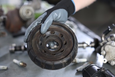 Photo of Auto part. Professional mechanic with strut mount at table indoors, closeup