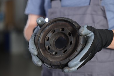 Photo of Auto part. Professional mechanic with strut mount indoors, closeup