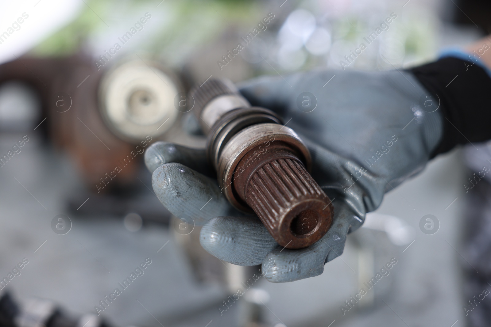 Auto part. Professional mechanic with drive shaft indoors, closeup. Space for text Photo of Auto part. Professional mechanic with drive shaft indoors, closeup. Space for text