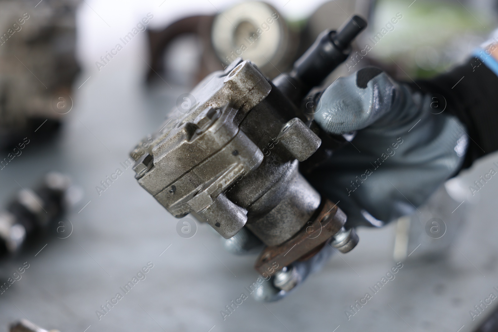 Auto part. Professional mechanic with power steering pump indoors, closeup Photo of Auto part. Professional mechanic with power steering pump indoors, closeup