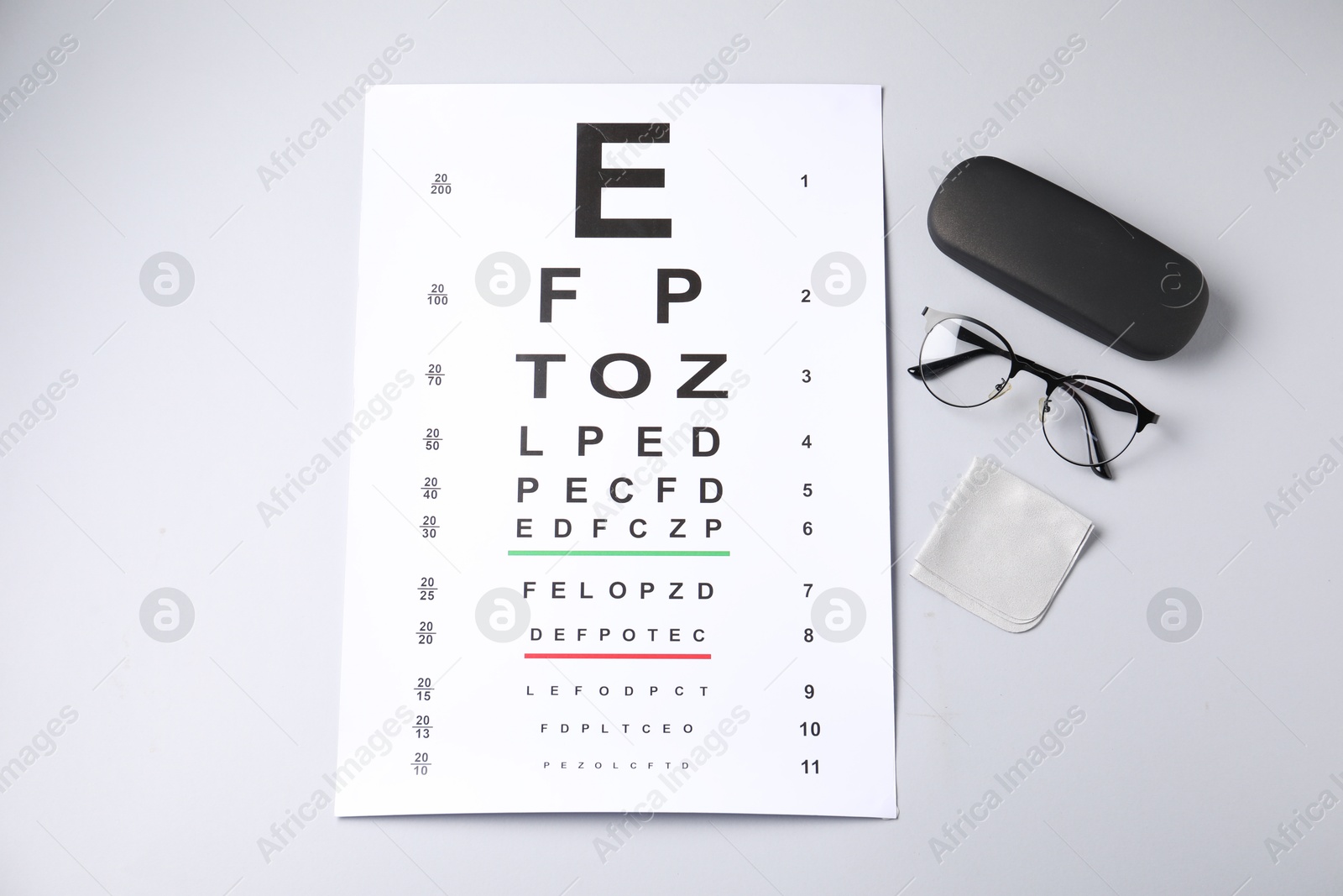 Vision test chart, glasses, case and cleaning cloth on white background, flat lay Photo of Vision test chart, glasses, case and cleaning cloth on white background, flat lay