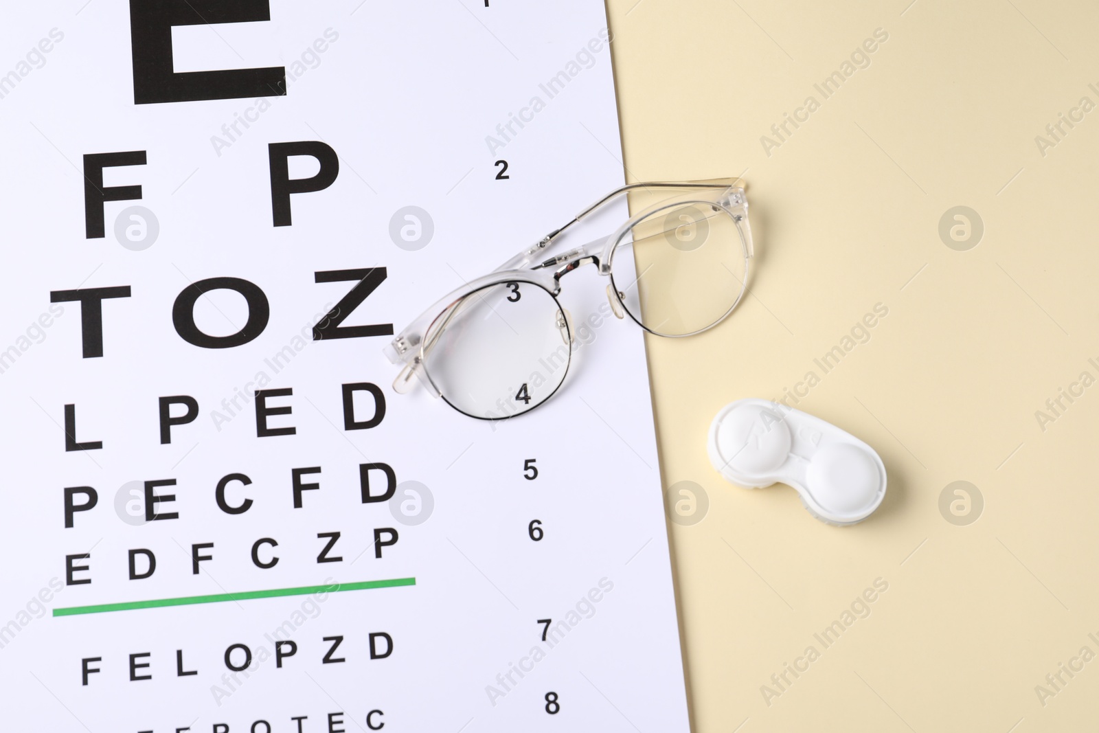 Vision test chart, glasses and lenses on beige background, above view Photo of Vision test chart, glasses and lenses on beige background, above view