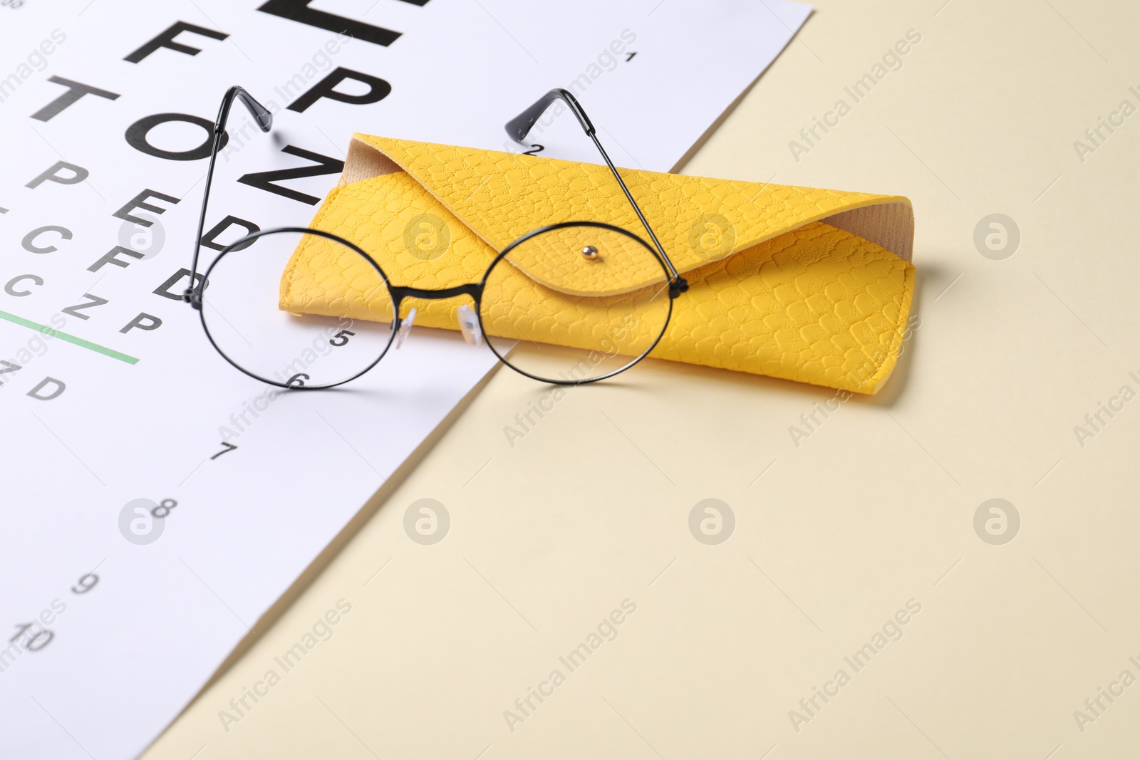 Vision test chart and glasses on beige background, closeup Photo of Vision test chart and glasses on beige background, closeup