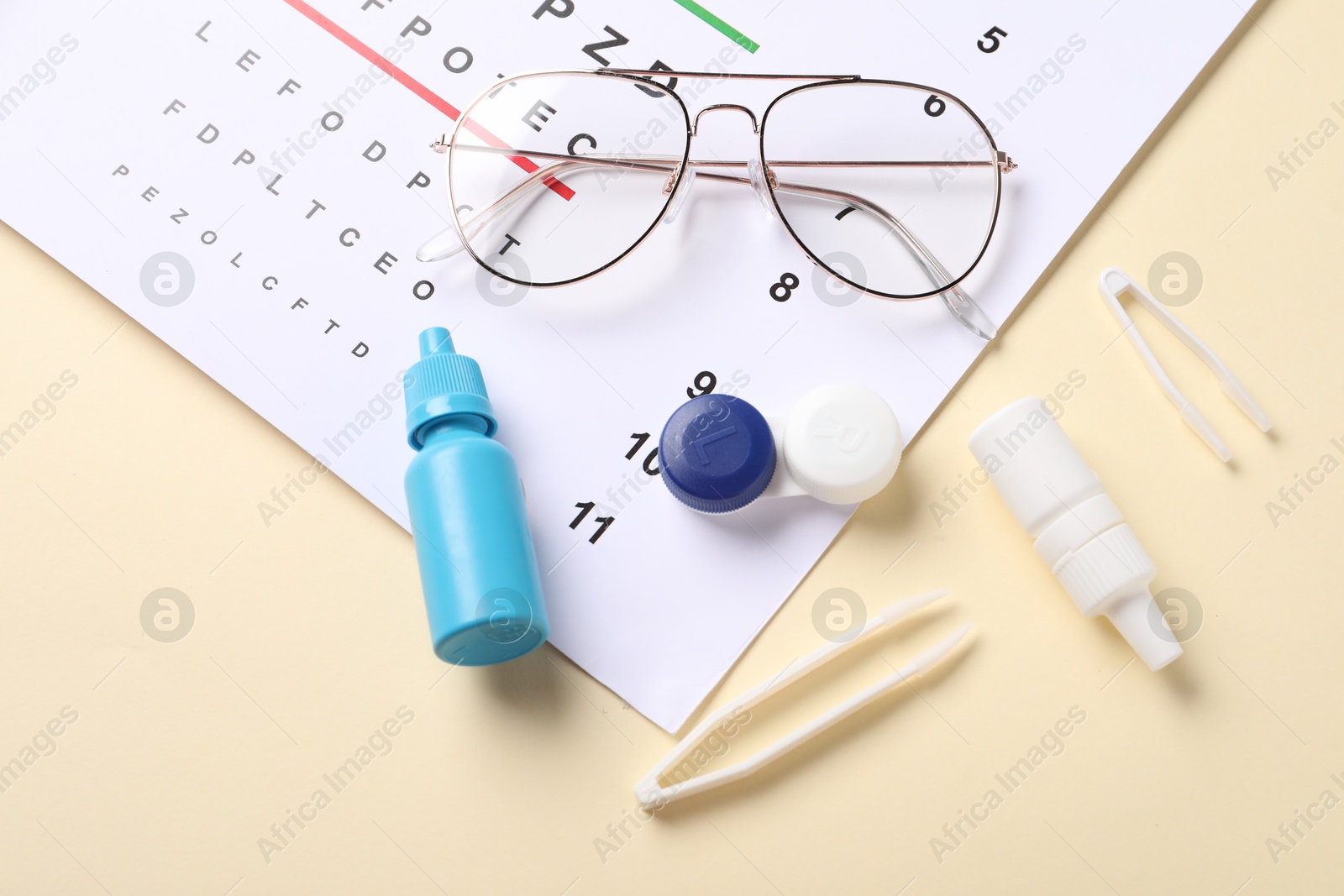 Vision test chart, glasses, tweezers, lenses and bottles of medical drops on beige background, flat lay Photo of Vision test chart, glasses, tweezers, lenses and bottles of medical drops on beige background, flat lay