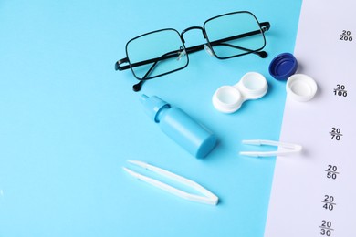 Photo of Vision test chart, glasses, tweezers, lenses and bottle of medical drops on light blue background, above view. Space for text