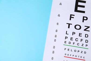 Photo of Vision test chart on light blue background, top view. Space for text