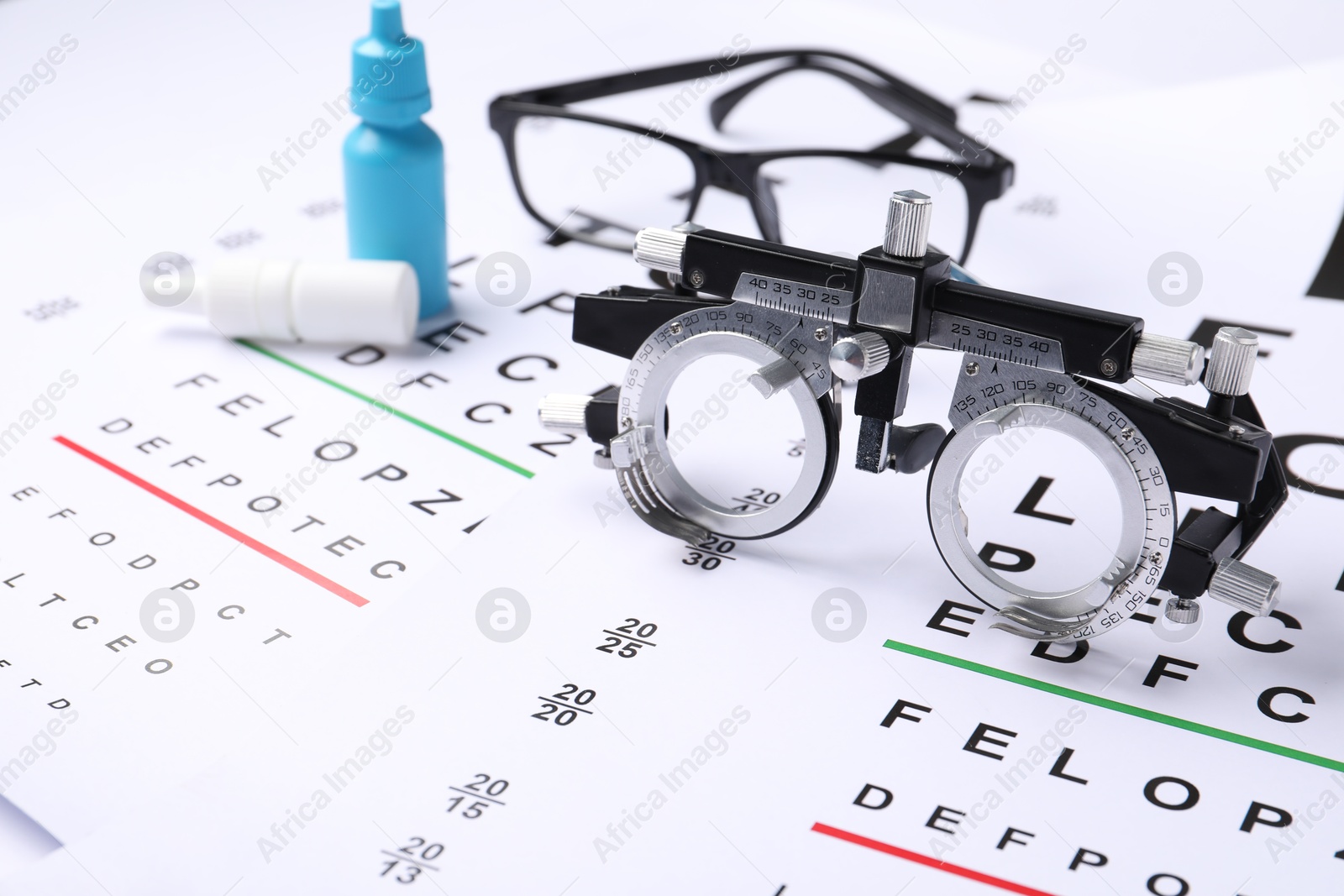 Glasses, trial frame and bottles of medical drops on vision test charts, closeup Photo of Glasses, trial frame and bottles of medical drops on vision test charts, closeup