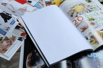 Photo of Different trendy magazines on wooden table, closeup