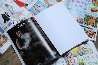 Photo of Different trendy magazines on wooden table, closeup