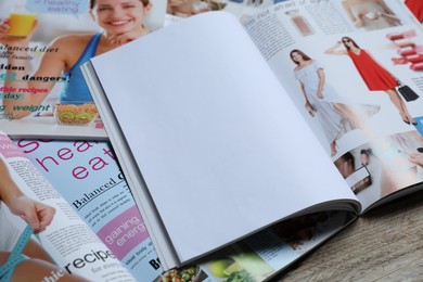 Photo of Different trendy magazines on wooden table, closeup