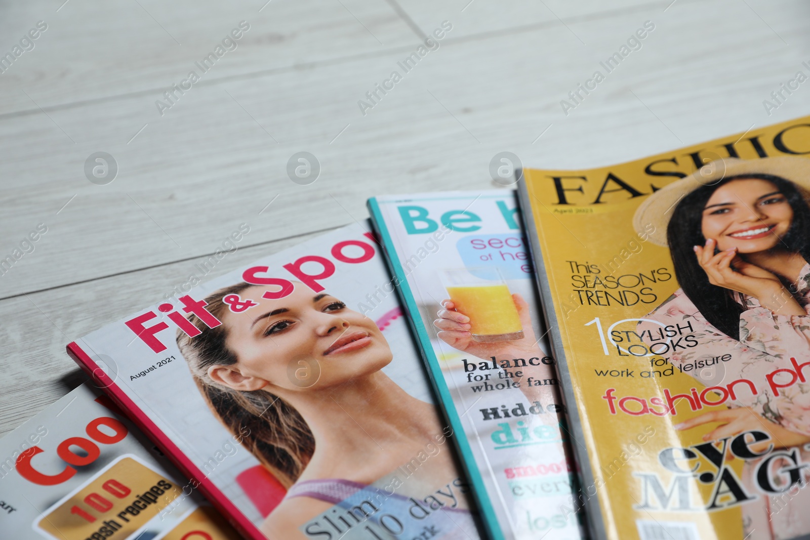 Different trendy magazines on white wooden table, closeup. Space for text Photo of Different trendy magazines on white wooden table, closeup. Space for text