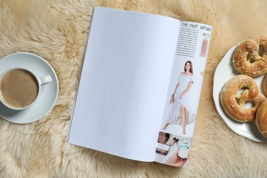 Photo of Open magazine, coffee and pretzels on faux fur, flat lay. Mockup for design