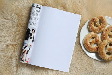 Photo of Open magazine and pretzels on faux fur, top view. Mockup for design