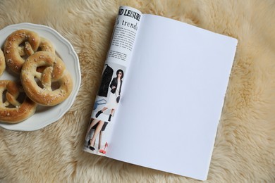 Photo of Open magazine and pretzels on faux fur, top view. Mockup for design