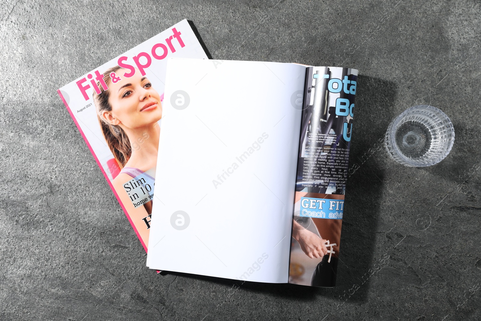 Photo of Trendy magazines and glass of water on grey background, top view. Mockup for design