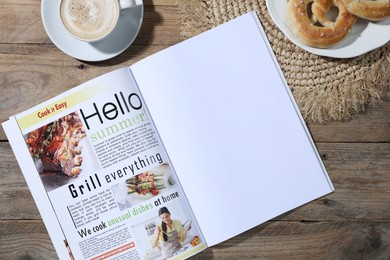 Photo of Open magazine, pretzels and coffee on wooden background, flat lay. Mockup for design
