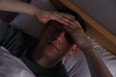 Photo of Frustrated man suffering from insomnia in bed indoors, top view