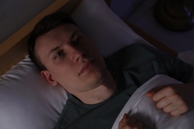 Photo of Frustrated man suffering from insomnia in bed indoors, top view