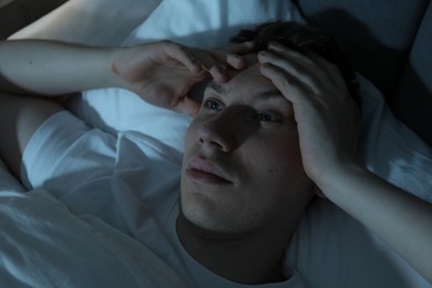Photo of Frustrated man suffering from insomnia in bed indoors, above view