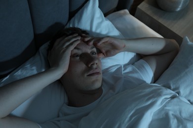 Photo of Frustrated man suffering from insomnia in bed indoors, above view