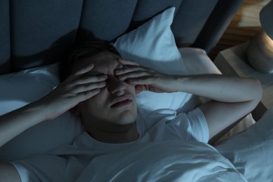 Photo of Frustrated man suffering from insomnia in bed indoors, above view