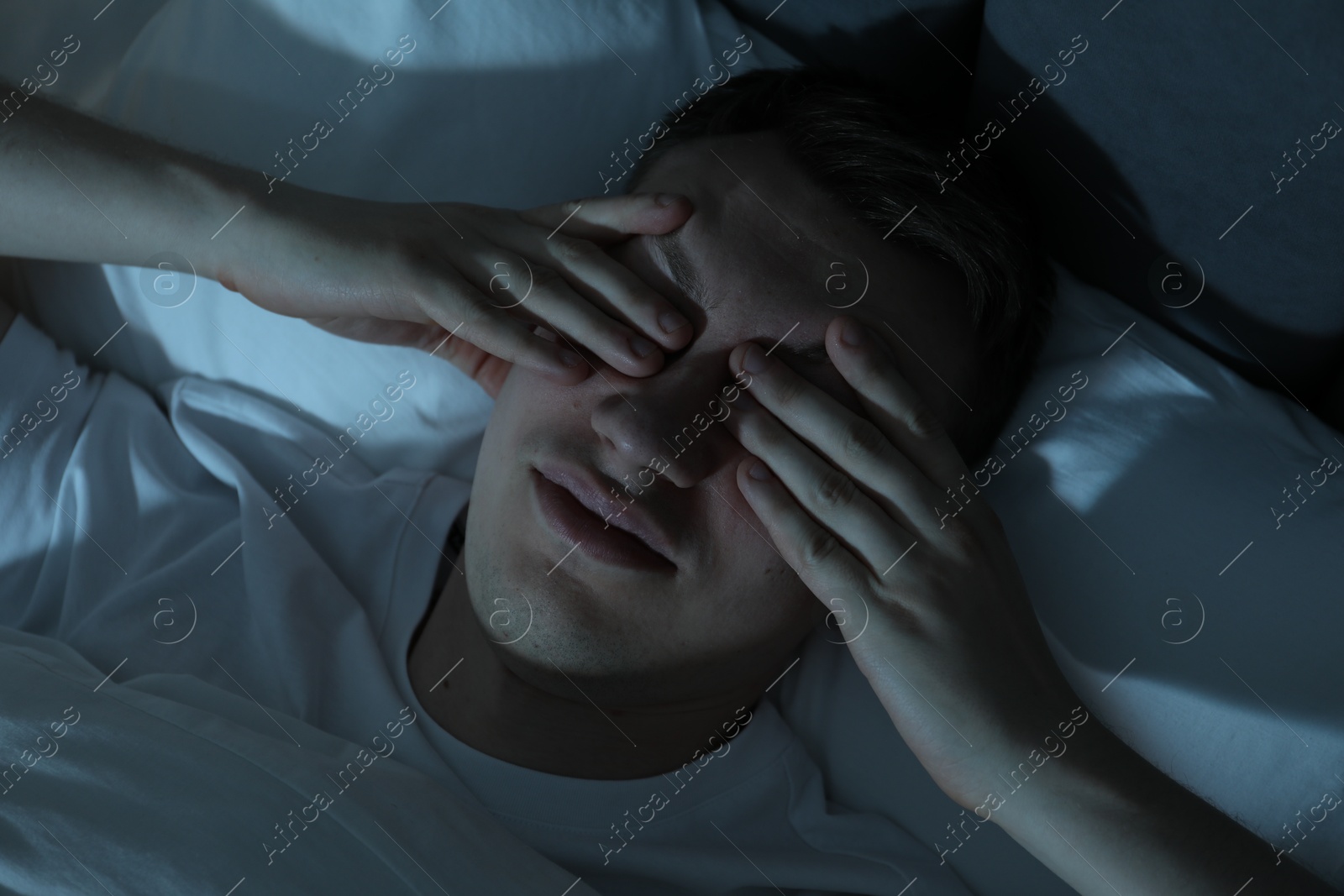 Photo of Frustrated man suffering from insomnia in bed indoors, top view