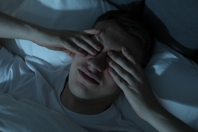 Photo of Frustrated man suffering from insomnia in bed indoors, top view