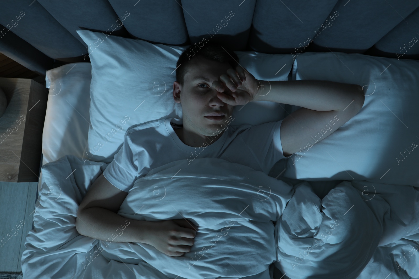 Photo of Frustrated man suffering from insomnia in bed indoors, top view