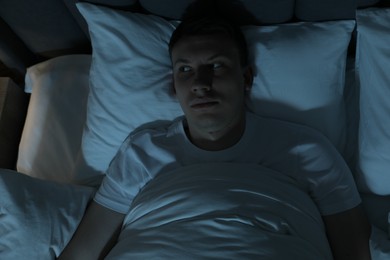 Photo of Frustrated man suffering from insomnia in bed indoors, top view