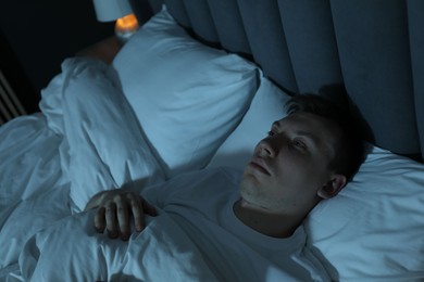 Photo of Frustrated man suffering from insomnia in bed indoors