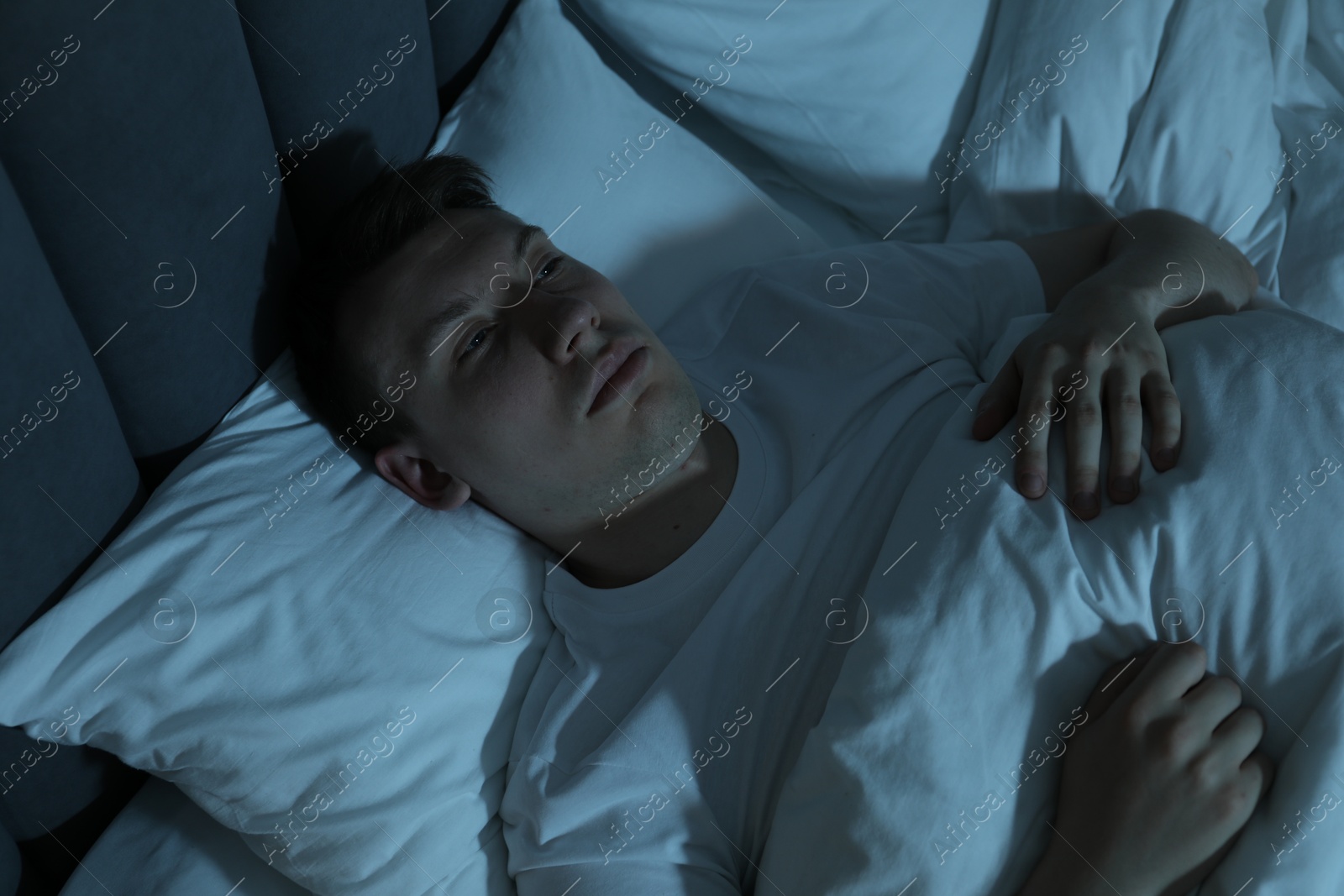 Photo of Frustrated man suffering from insomnia in bed indoors, above view