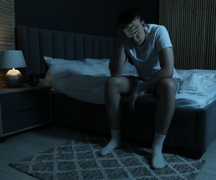 Photo of Frustrated man suffering from insomnia on bed indoors