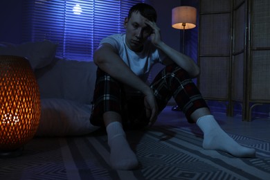 Photo of Frustrated man suffering from insomnia on floor indoors