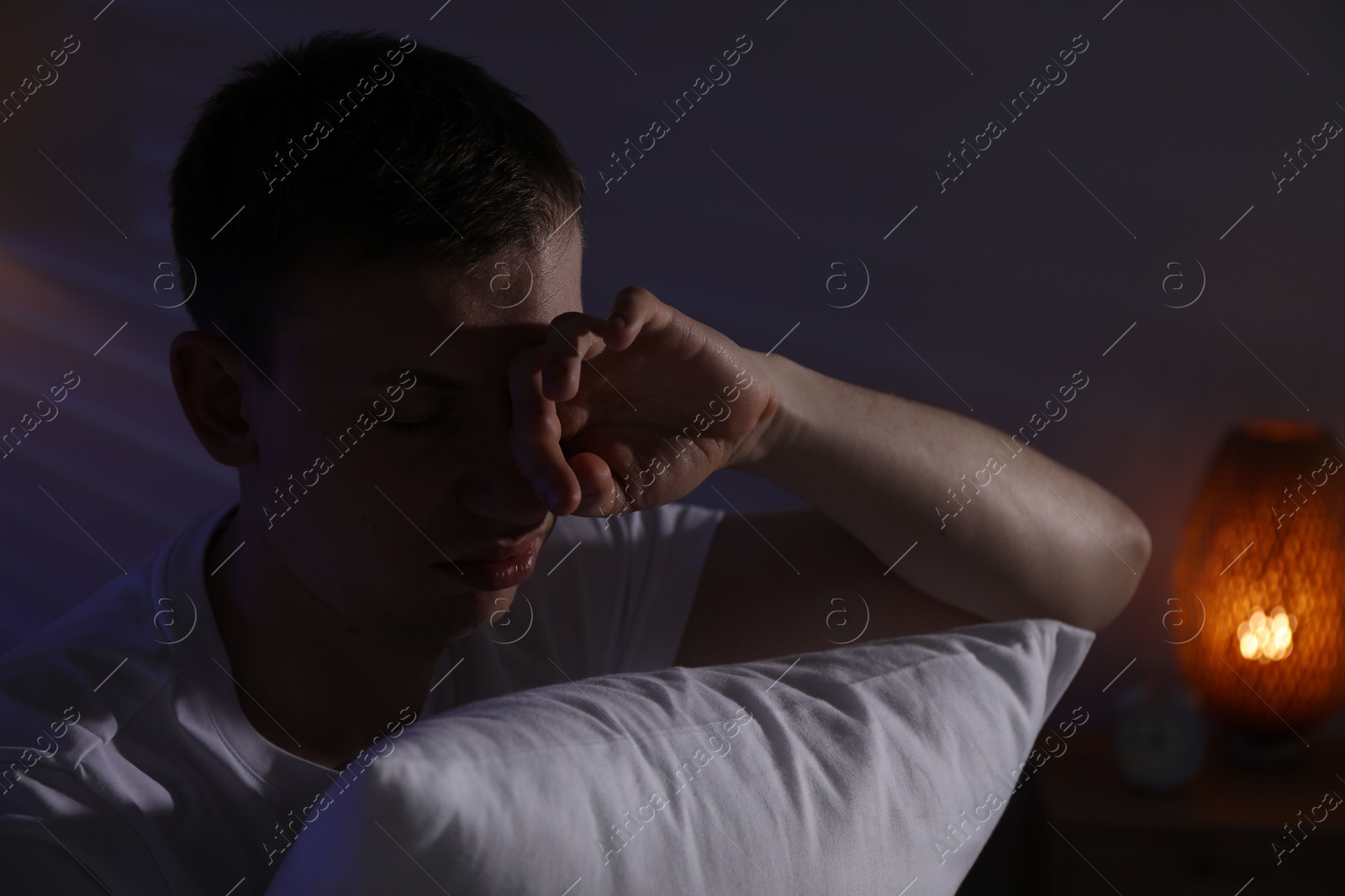 Photo of Frustrated man with pillow suffering from insomnia indoors